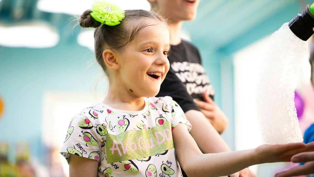 a little girl is smiling and holding something in her hand